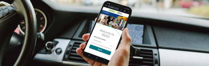 Person holding smartphone in car with MySGI website open
